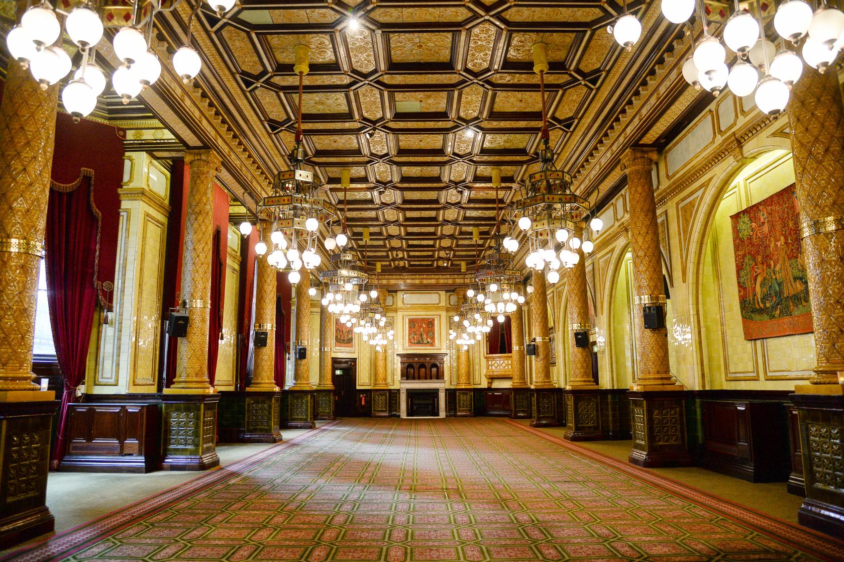 An event space with ornate chandeliers, patterned carpet, gilded columns, and high decorated ceilings at The Royal Horseguards & One Whitehall Place.