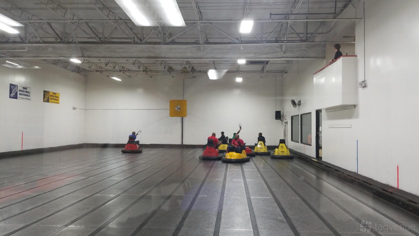 An event space with bumper cars, overhead lighting, and a referee booth at WhirlyBall/LaserWhirld of Plano.