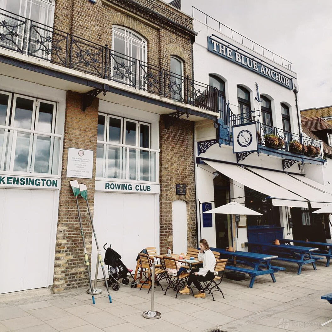 A versatile event space with brick exterior, large white doors, and outdoor seating at Auriol Kensington Rowing Club.
