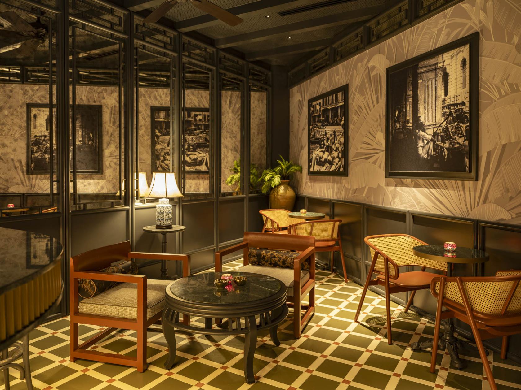 A hotel bar with patterned tile flooring, round black tables, wooden chairs, and framed wall art at The Robertson House by The Crest Collection.