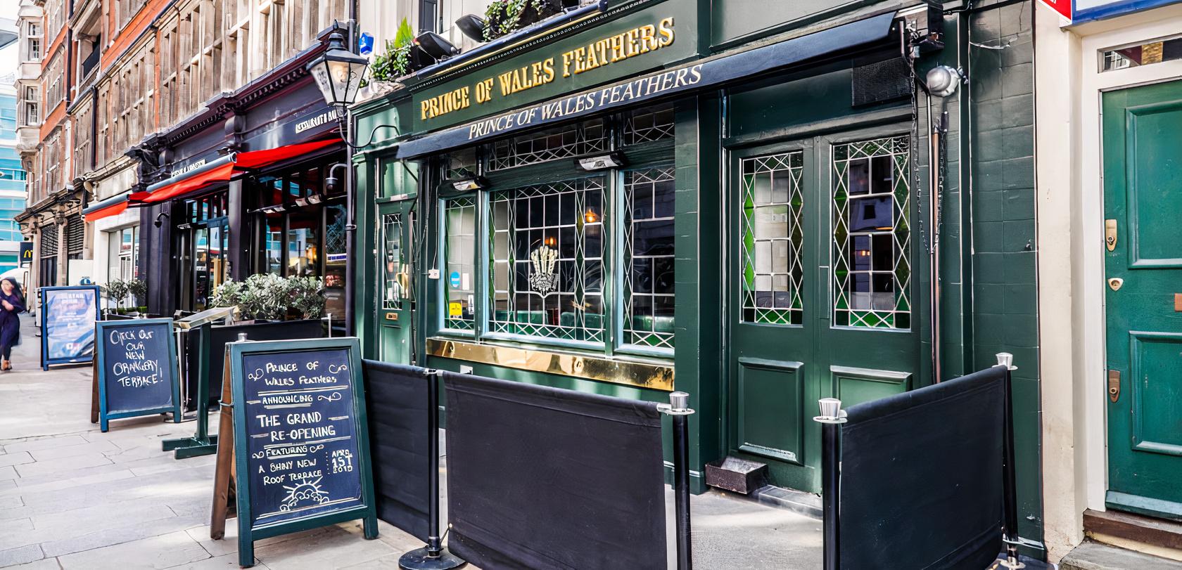 A traditional pub with dark green facade, stained glass windows, and gold signage at The Prince of Wales Feathers.