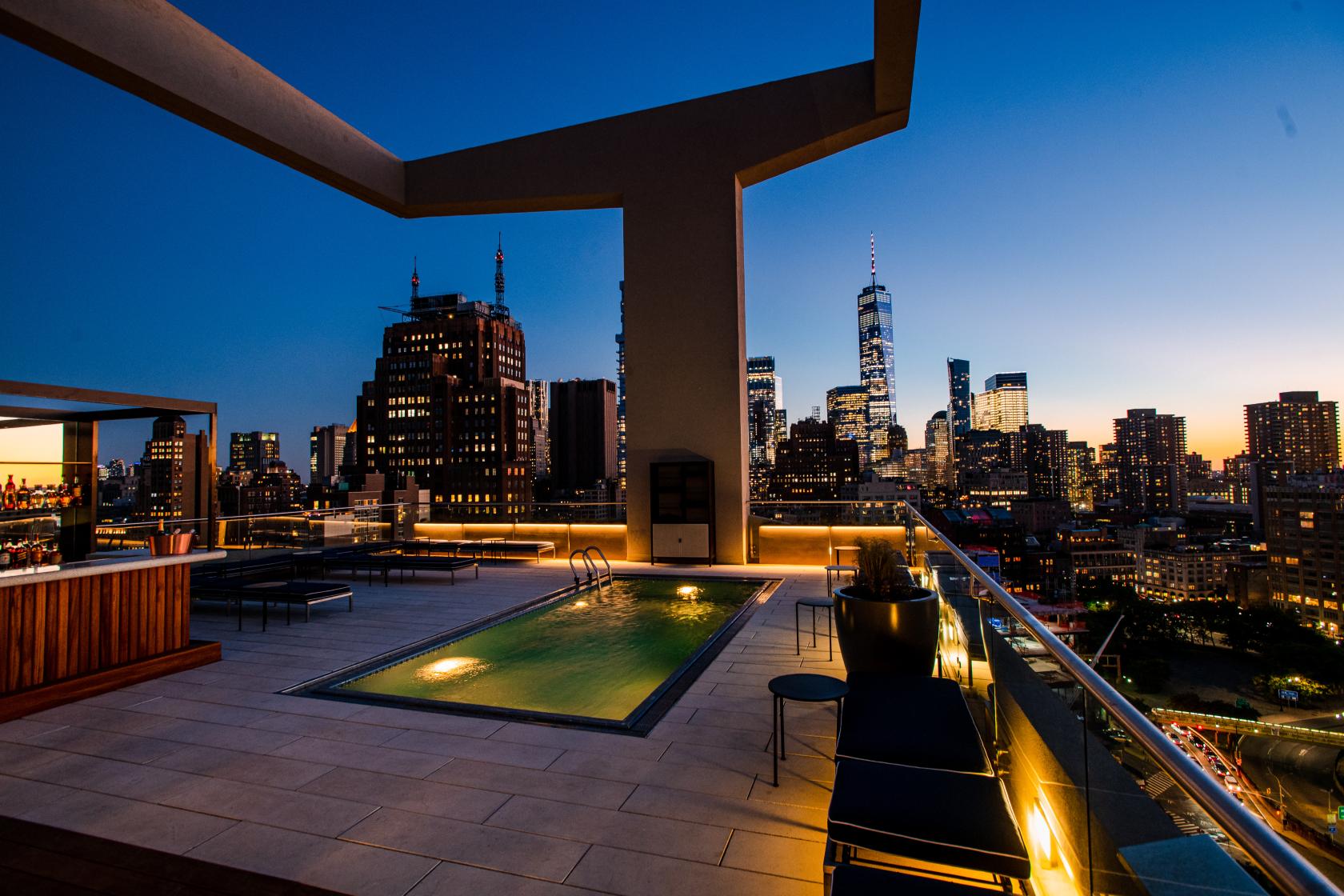 A hotel rooftop with a pool, outdoor bar, and skyline views at ModernHaus SoHo.