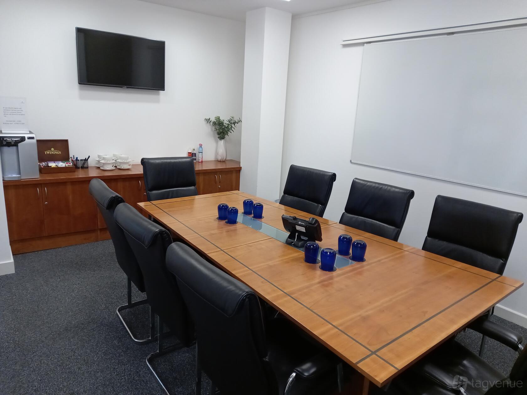A meeting room with a wooden conference table, leather chairs, a wall-mounted TV, and a whiteboard at Landmark: Luminous House.