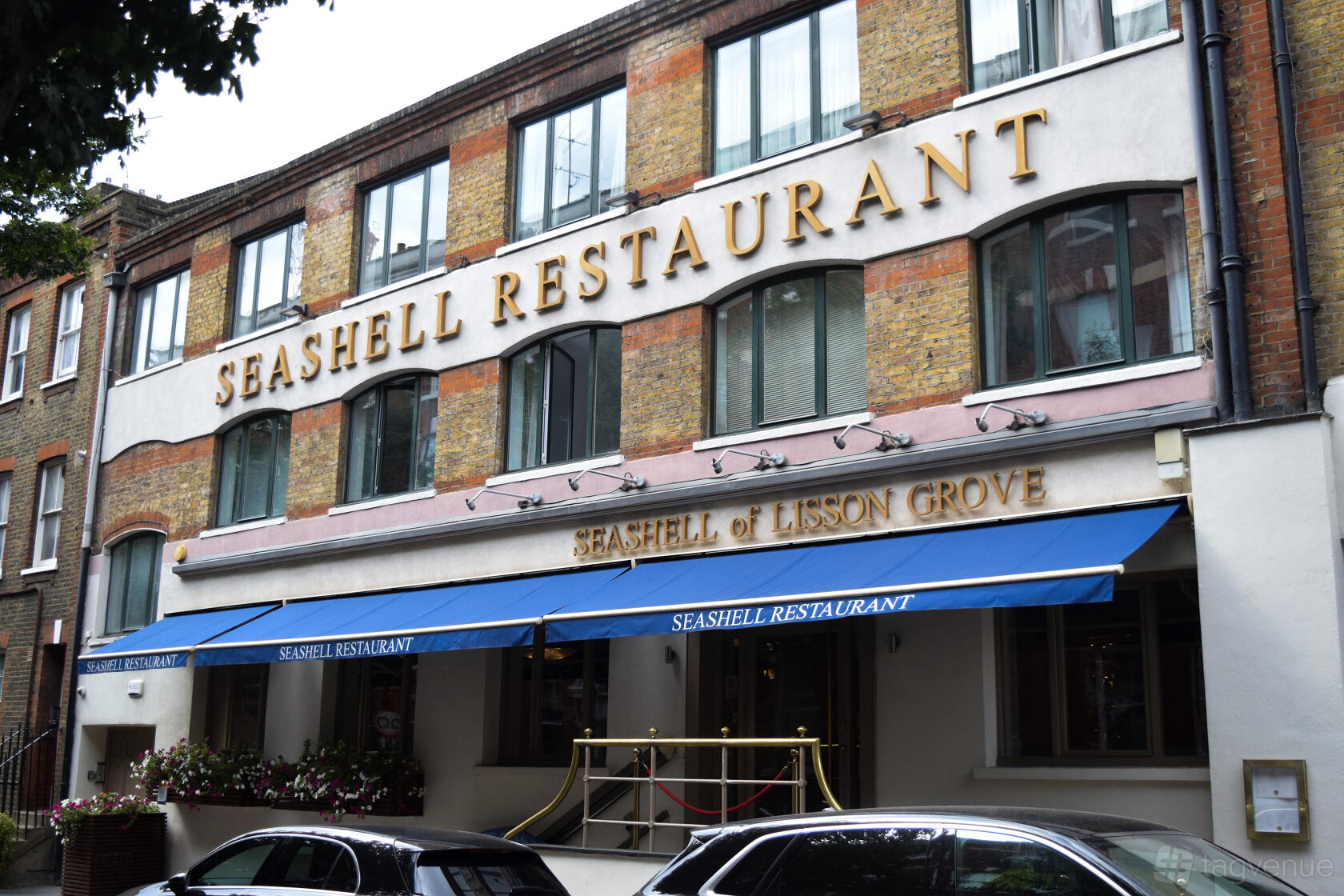 A restaurant with a brick facade, large windows, and blue awnings at The Seashell of Lisson Grove.