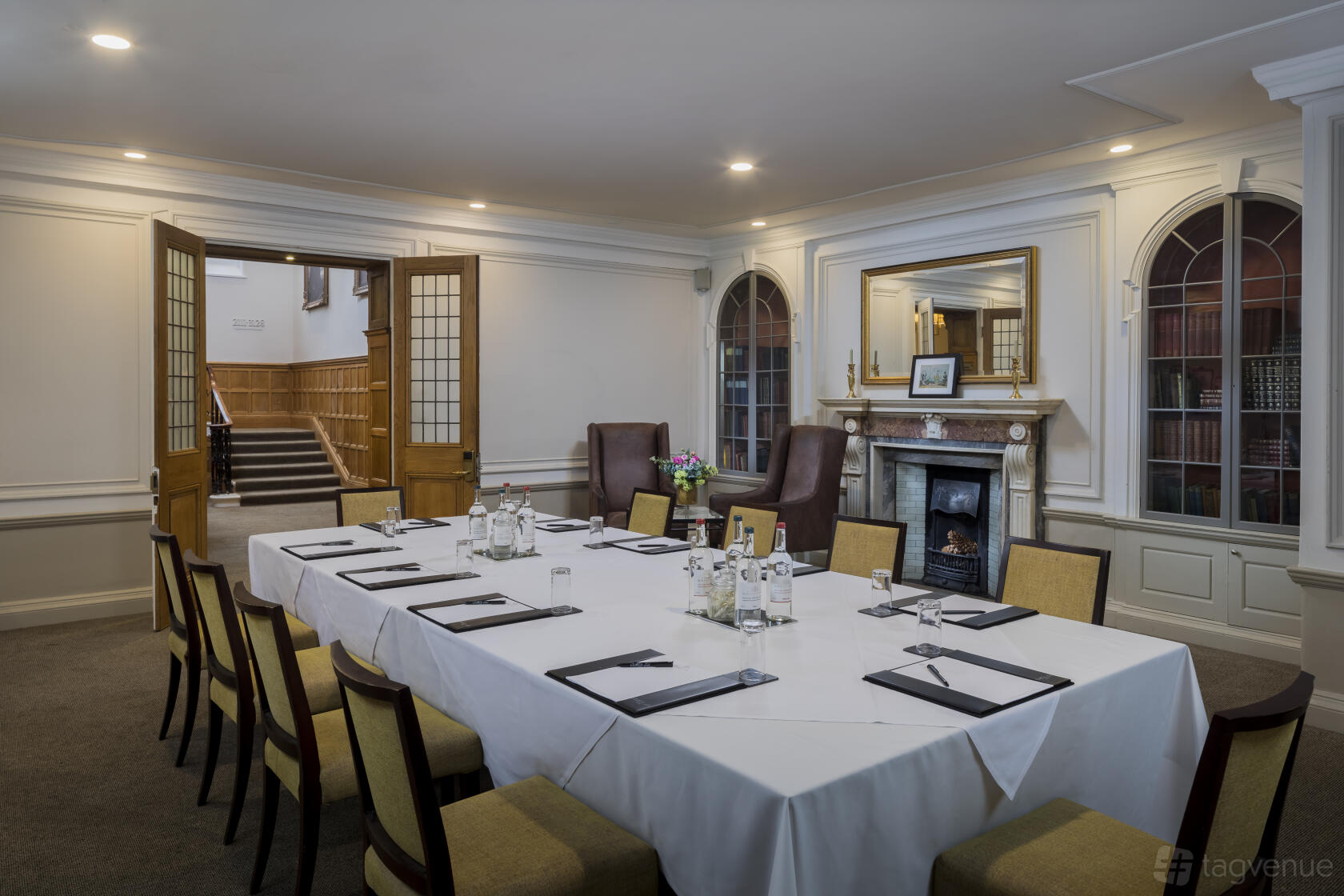 An event room with a long table set for a meeting, fireplace, and large windows at Oatlands Park Hotel.