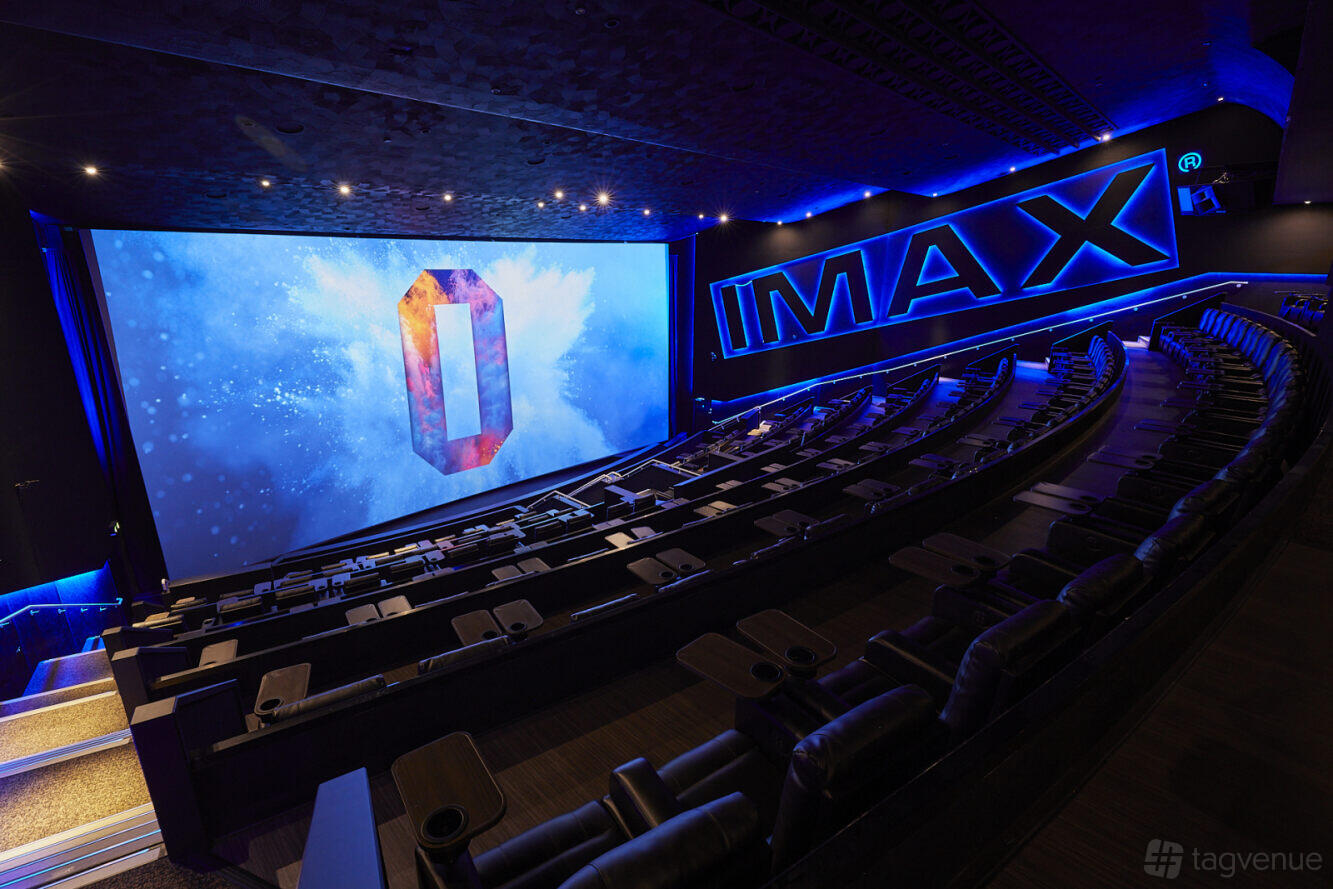 An auditorium with a large IMAX screen, tiered reclining seats, and blue LED lighting at ODEON LUXE Swiss Cottage.