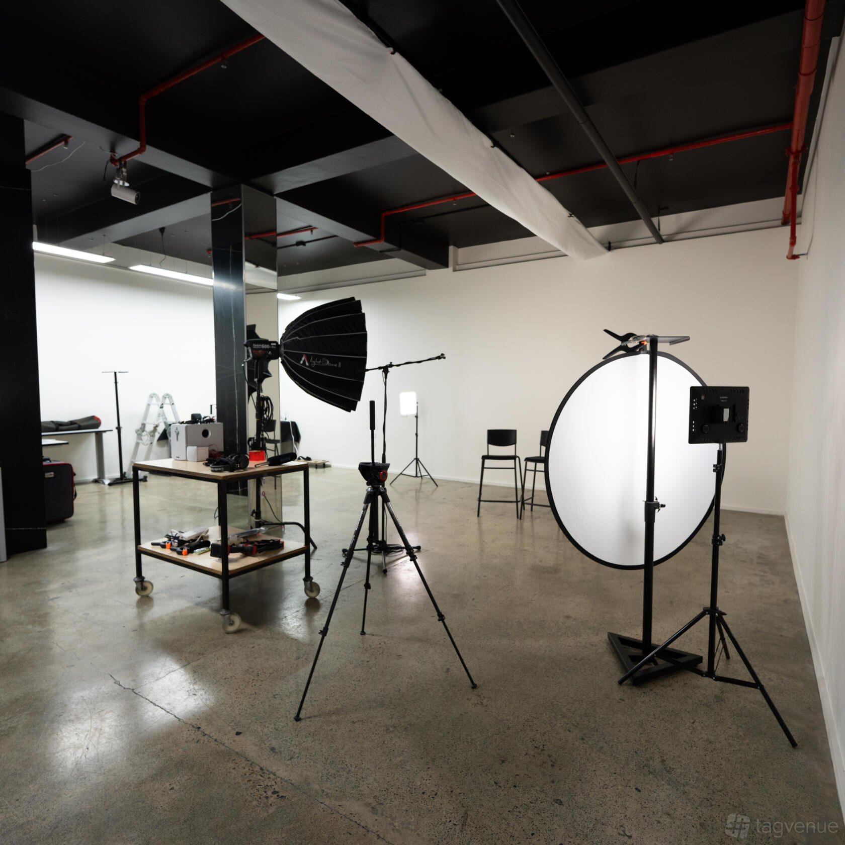 A film studio with a concrete floor, white walls, lighting equipment, and photography backdrops at Scroll Stop Studios.