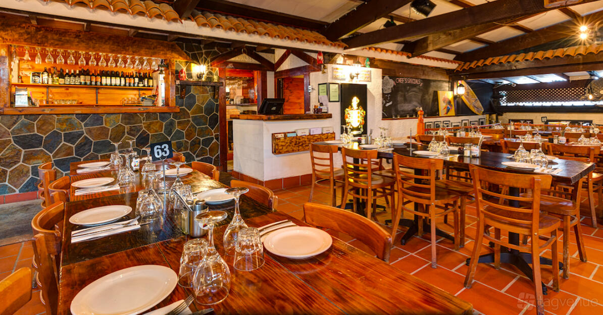 A restaurant with wooden tables set with glassware and tiled floors at Spanish Tapas.