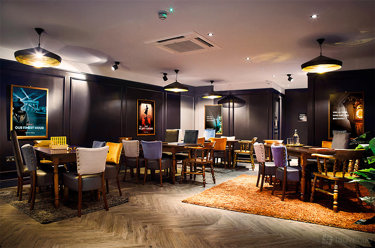 An event venue with dark paneled walls, colorful upholstered chairs, and game tables at The Escape Hunt Experience Melbourne.