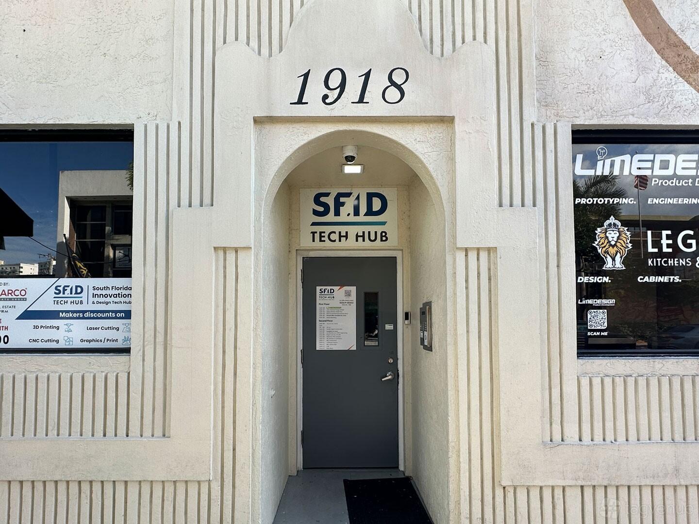 An exterior entrance with an arched doorway and SFID Tech Hub signage at Hustle Inspires Hustle.