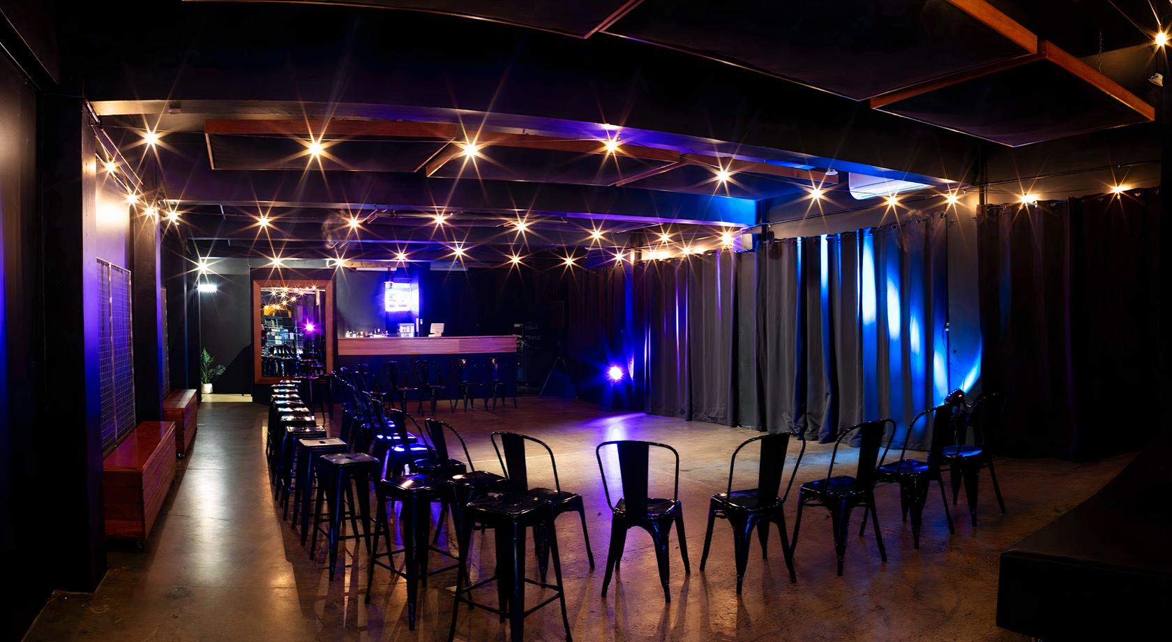 An event space with black chairs in rows, a polished concrete floor, and dramatic lighting at EC Venue.