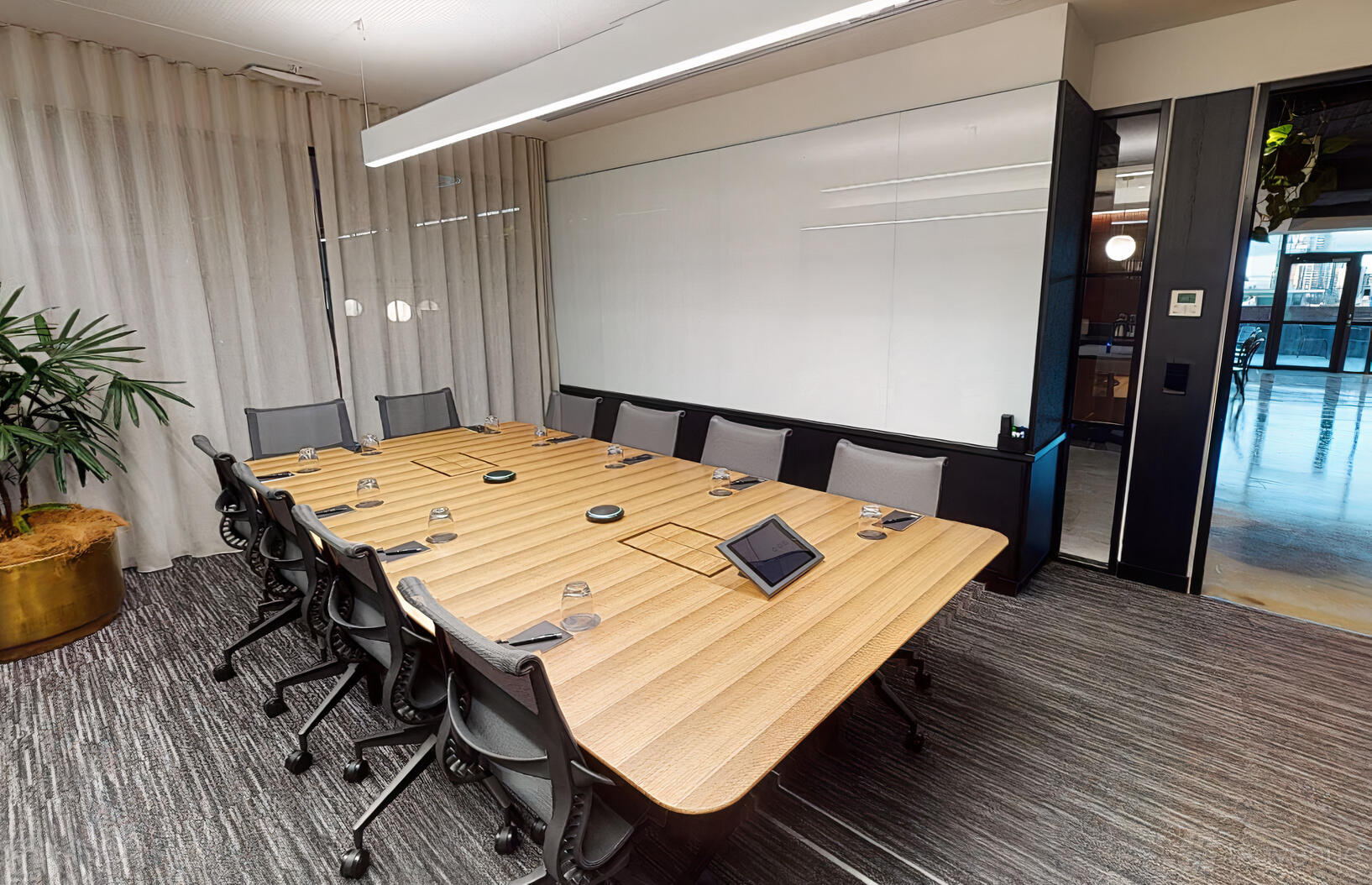 A coworking space with a long wooden conference table, ergonomic chairs, and a wall-length whiteboard at Hub Church Street.