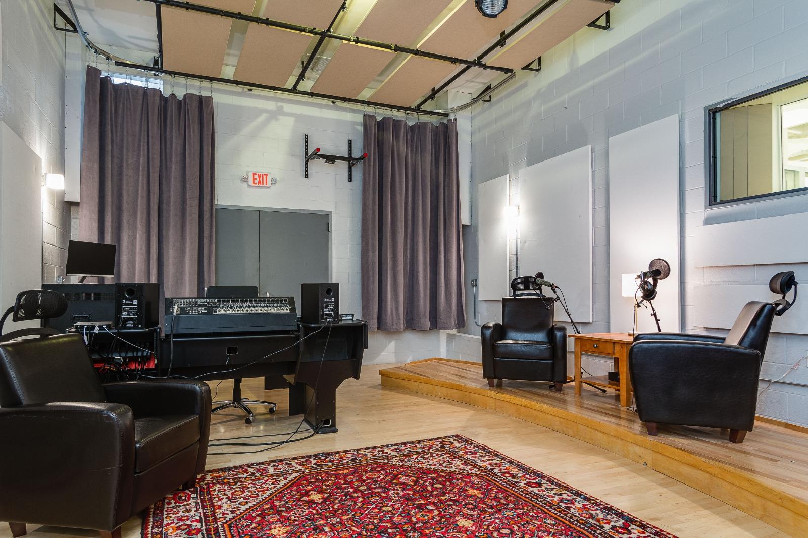 A coworking space with a recording studio setup, soundproofing panels, and lounge chairs at The Boulevard Arcade by CrossFunction.