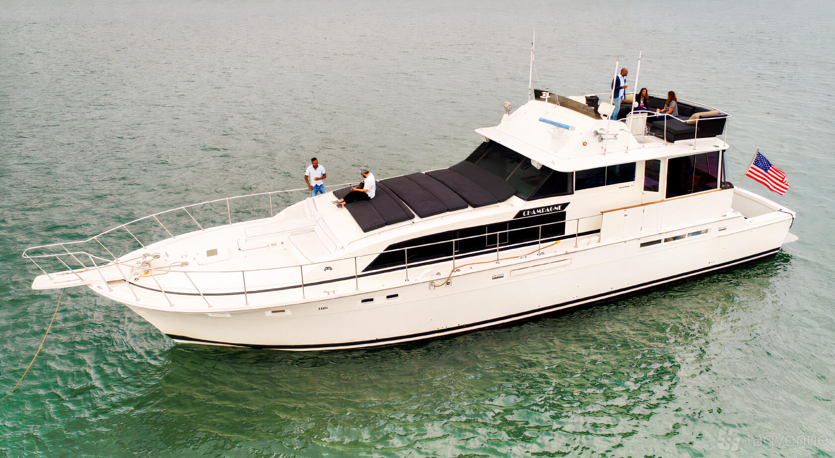 A yacht with an upper deck lounge area and railings on the water at Champagne Yacht.