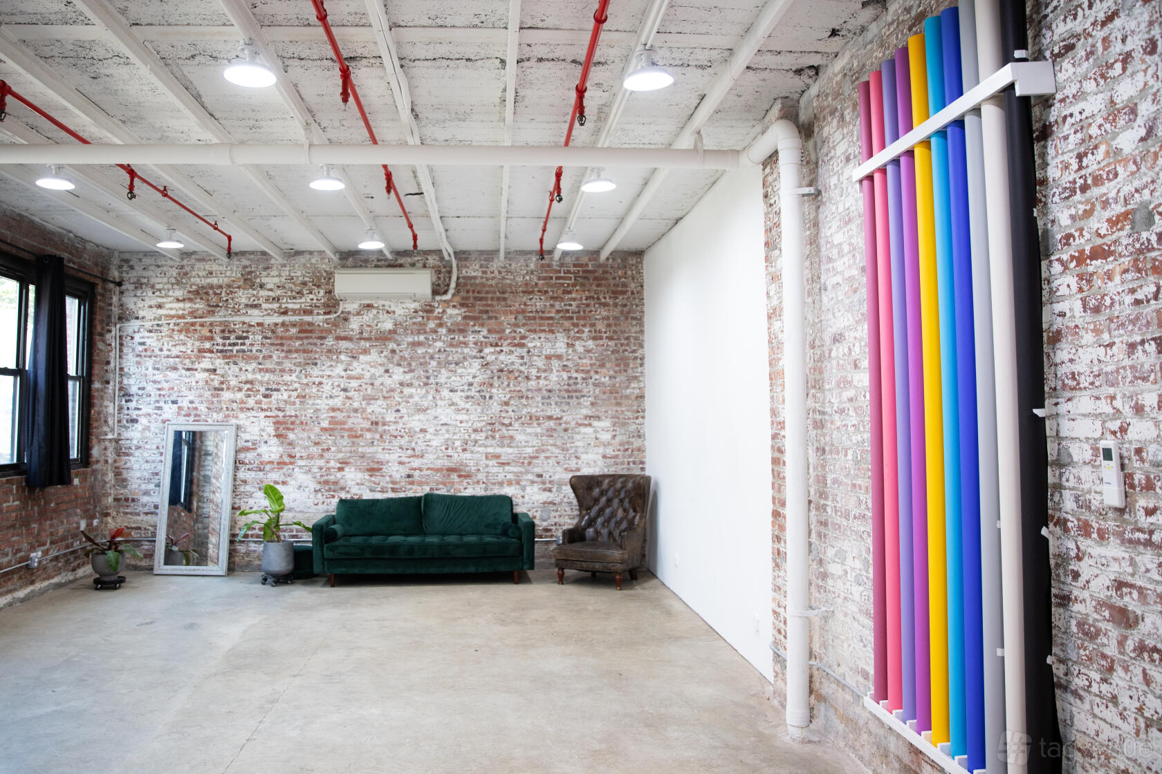 A photo studio with exposed brick walls, large windows, and colorful backdrop rolls at Matka LLC: LUSTRO.