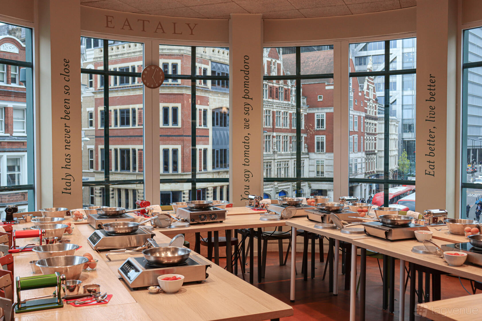 An event space with cooking stations, induction hobs, and large windows overlooking city streets at Eataly London.
