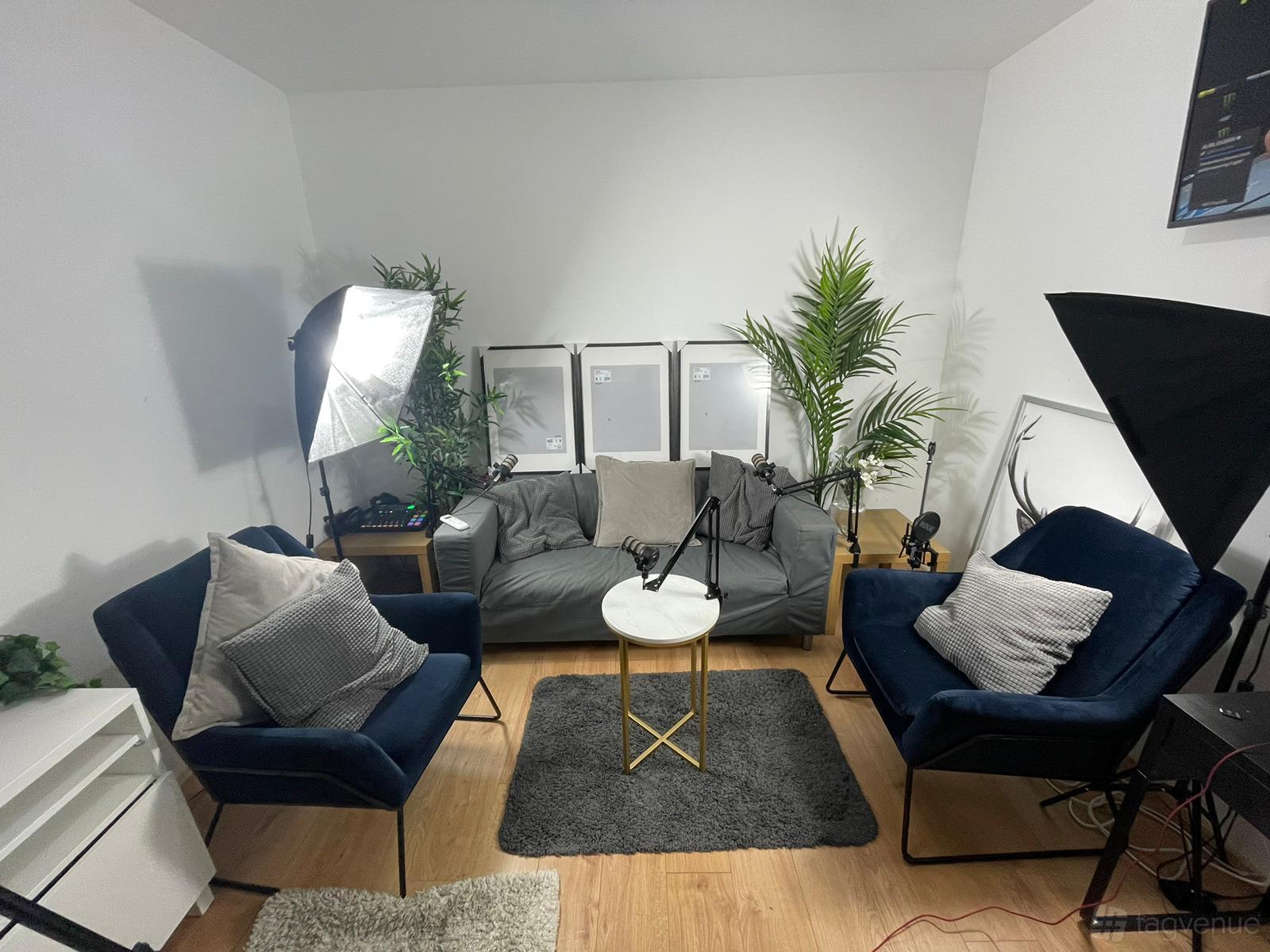 A recording studio with a sofa, two armchairs, potted plants, and photography lighting at DB Studios.