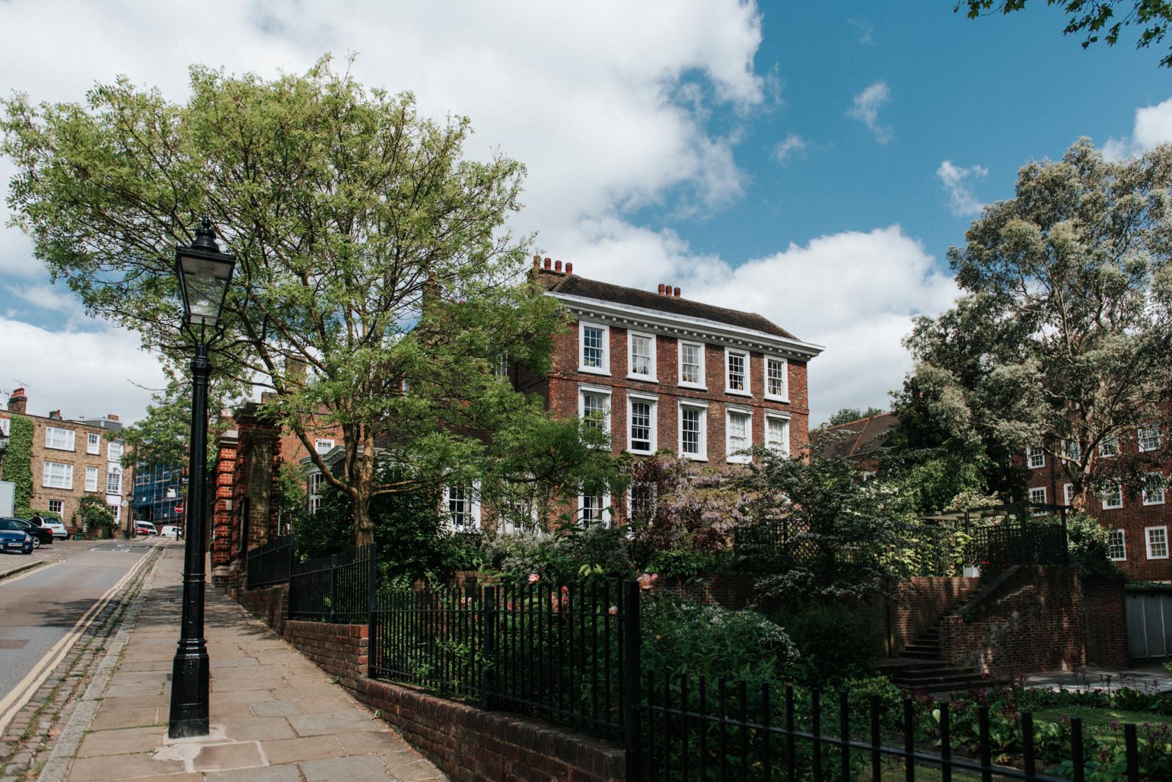 A historic museum with red brick Georgian architecture and a leafy garden exterior at Burgh House & Hampstead Museum.