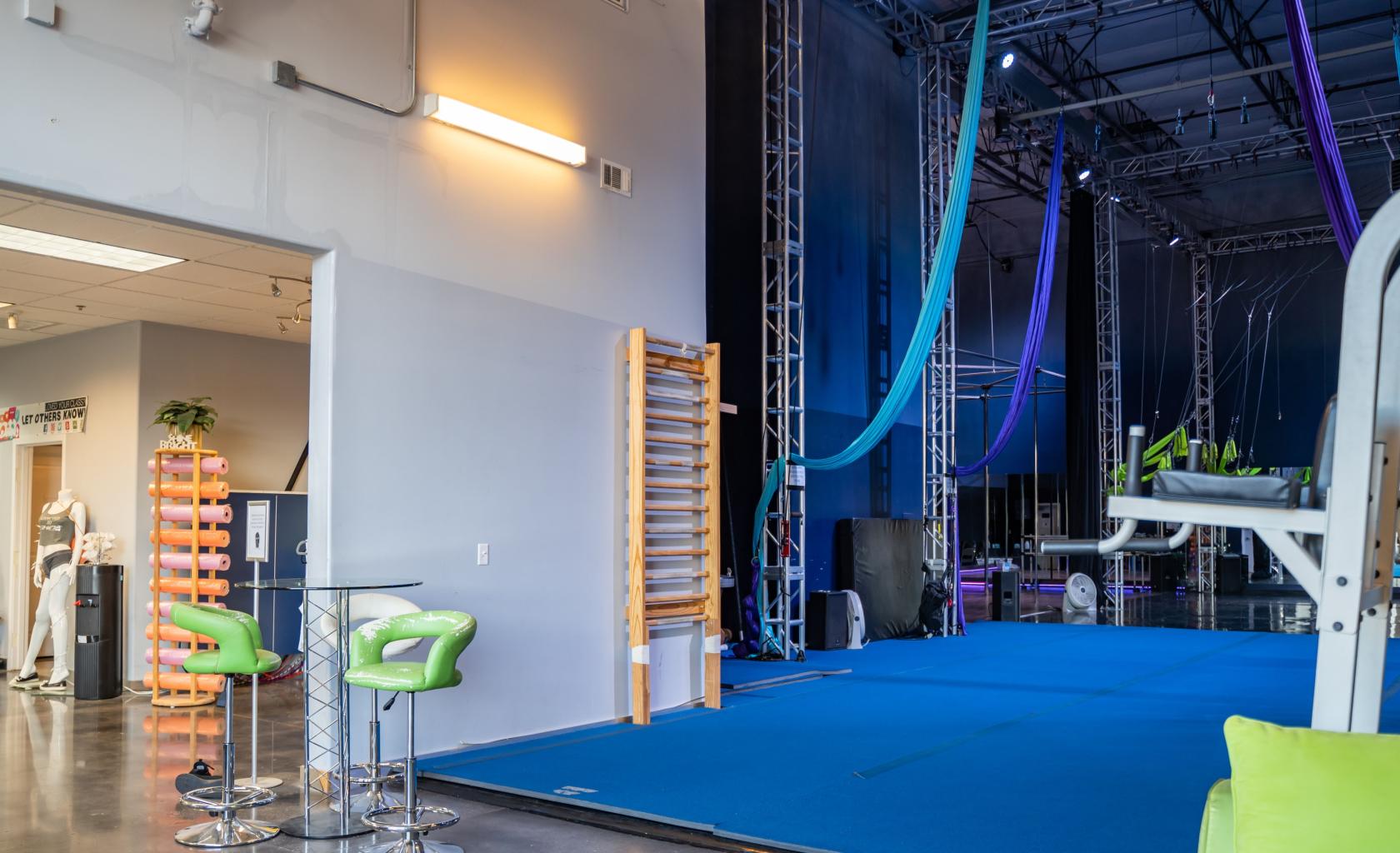 An event venue with aerial silks, blue mats, and high ceilings at Shine Alternative Fitness.