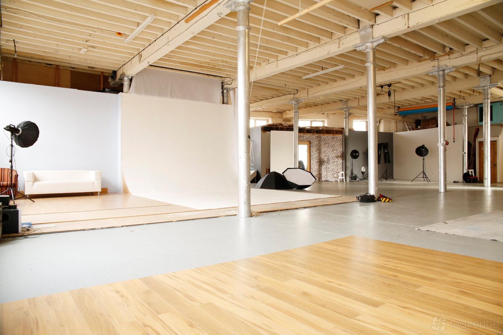 A photo studio with white backdrops, exposed beams, photography lights, and a white sofa at Silkwood Studio.