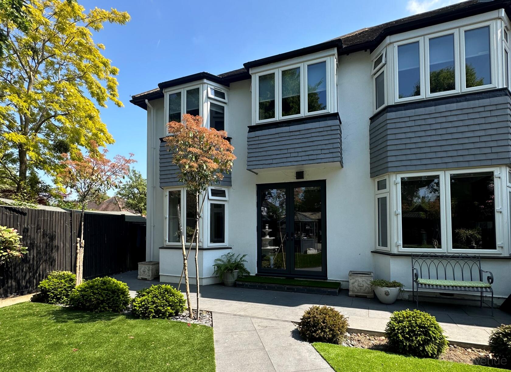 A country house with gray shingle siding, large windows, and a landscaped front garden at Home for Photo & Video Shoots.
