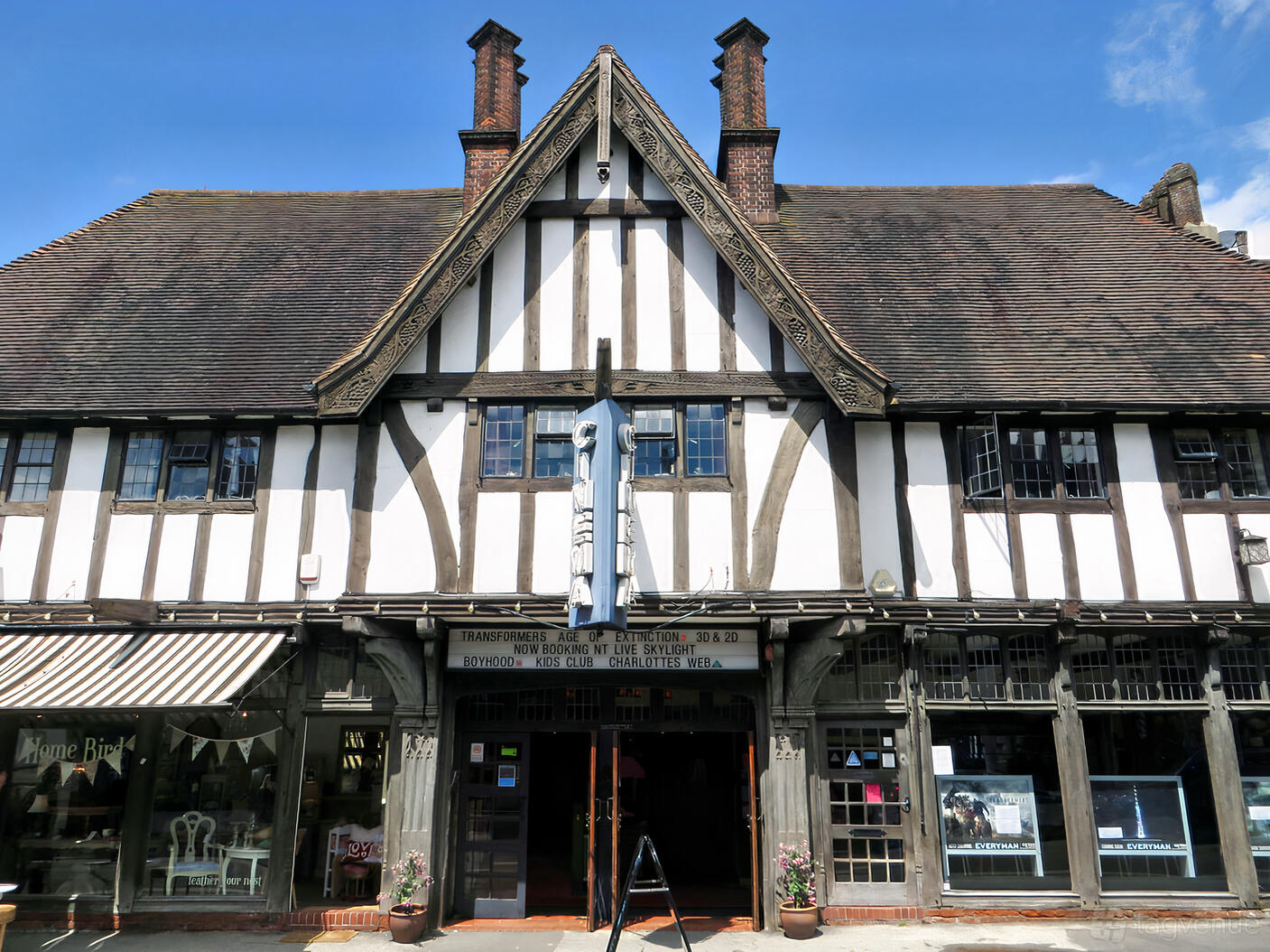 A Tudor-style cinema exterior with half-timbered facade, tall chimneys, and marquee at Everyman Oxted.