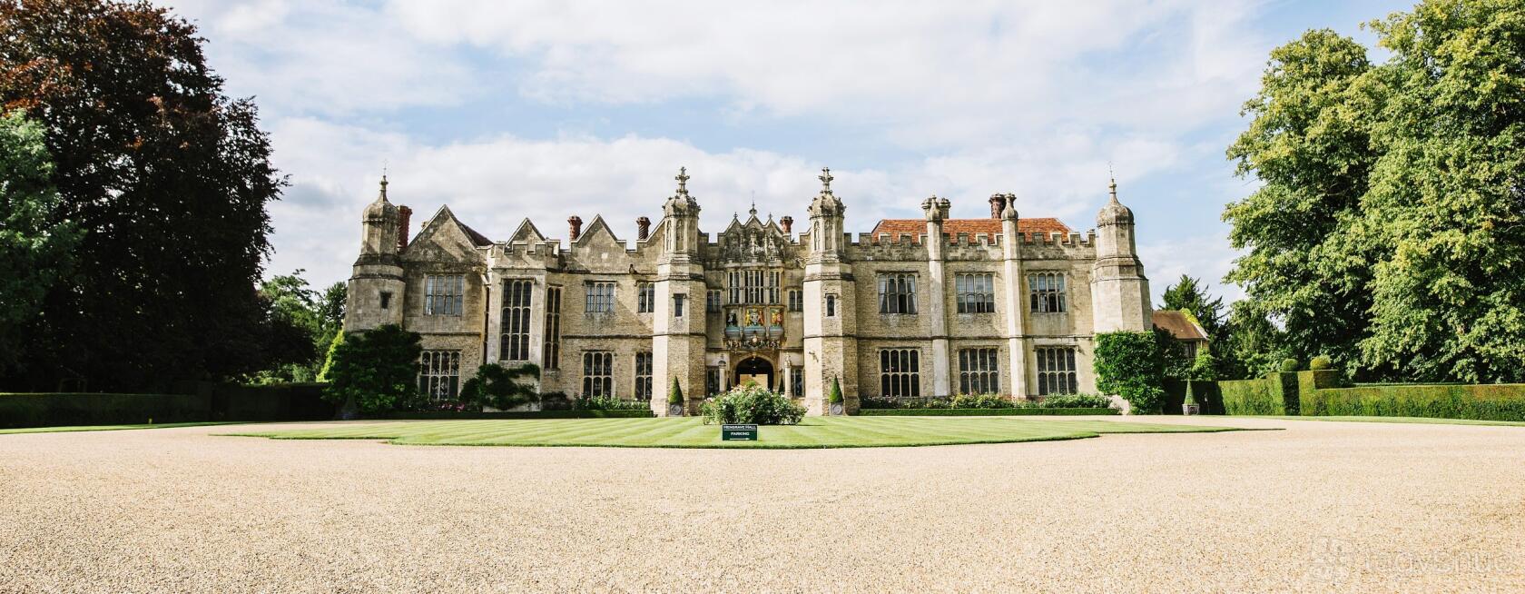 A historic manor with stone facade, manicured lawn, and ornate detailing at Hengrave Hall.