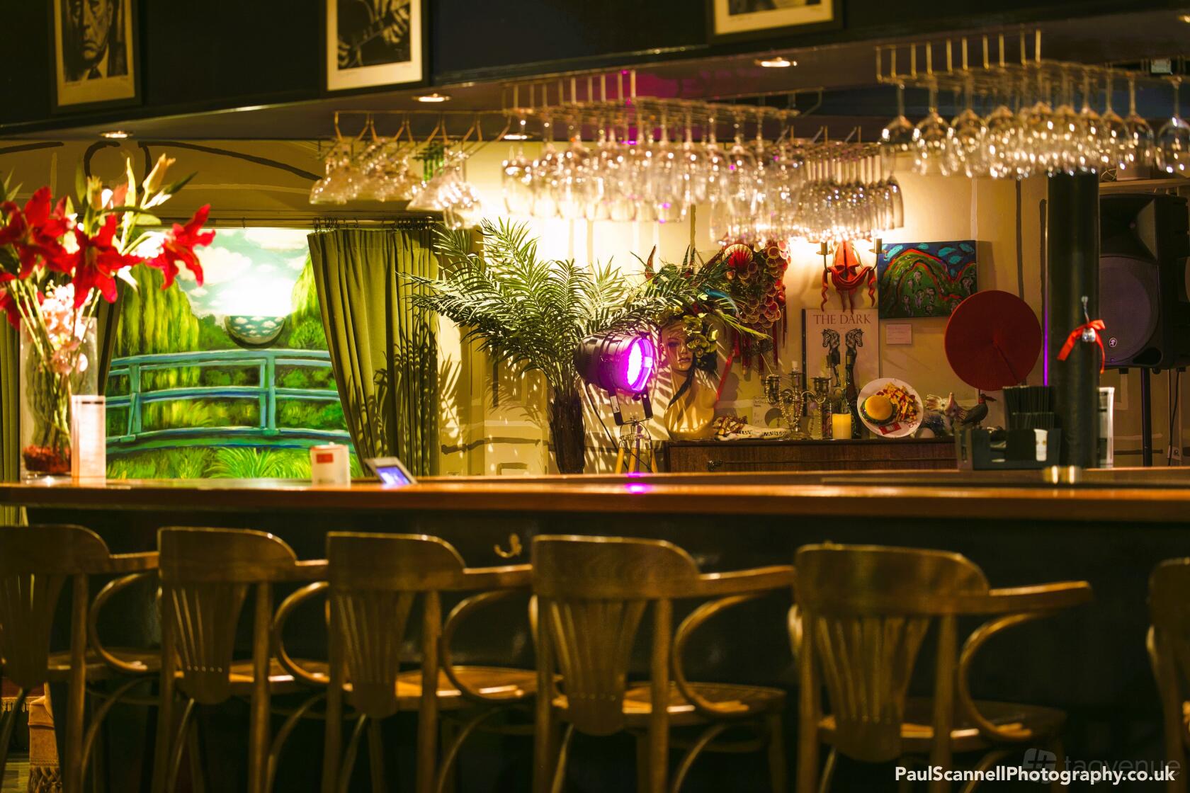 An event venue with a long wooden bar, hanging glassware, and eclectic decor at Vout-O-Reenees.
