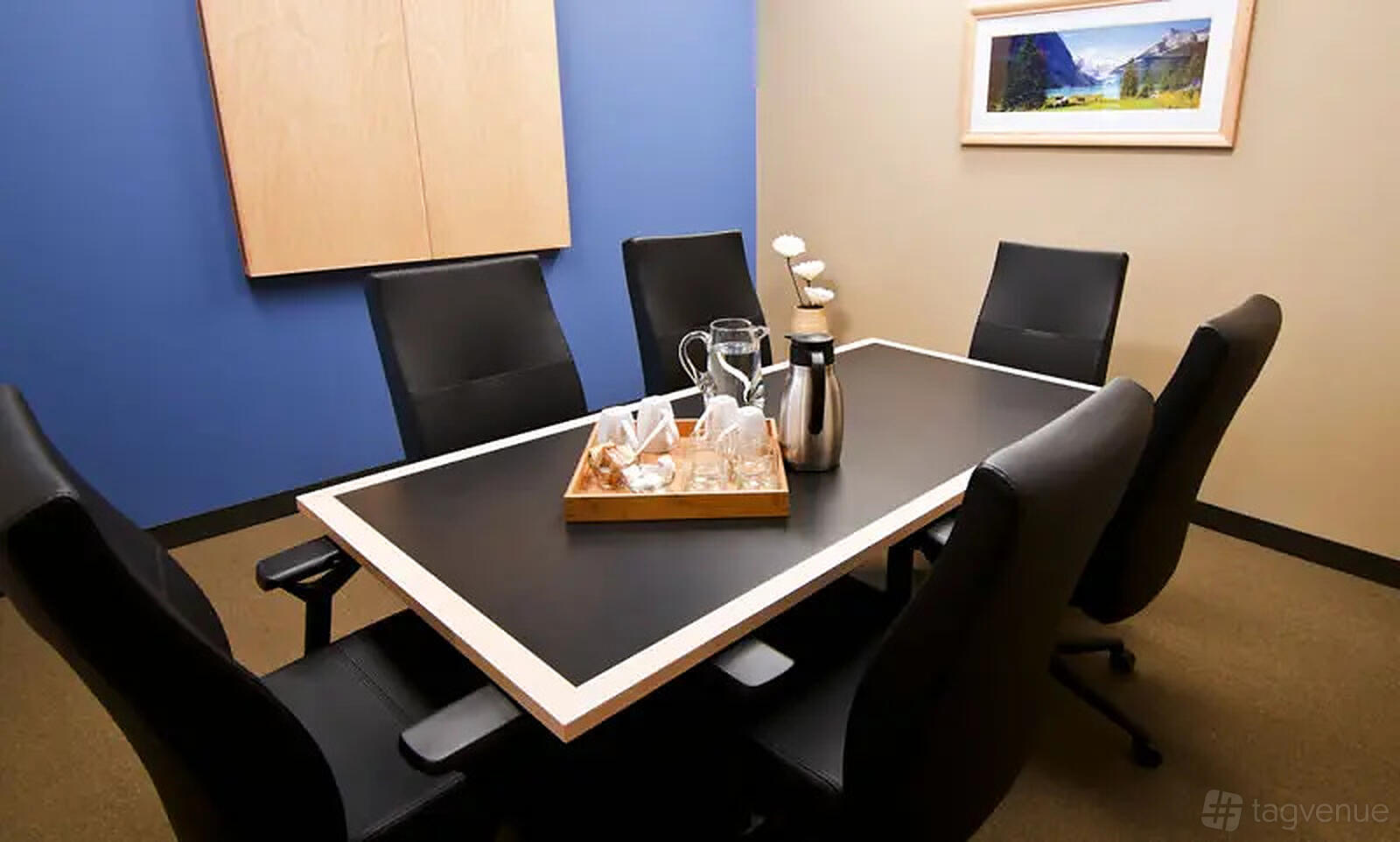 A meeting room with a rectangular table, six black chairs, and a tray with glassware at Intelligent Office Dallas (Las Colinas).