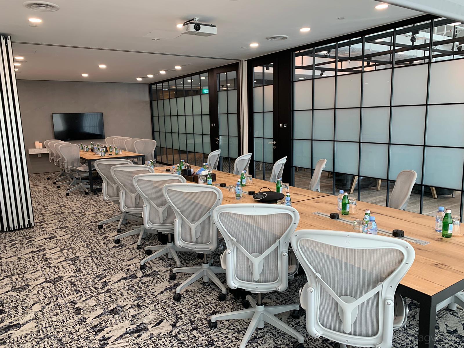 A meeting room with ergonomic chairs, a long wooden conference table, and frosted glass partition walls at Ocean Financial Centre.