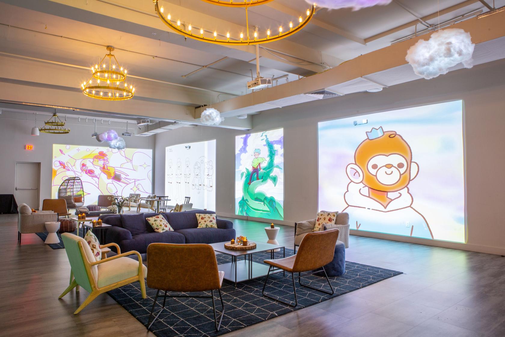 A loft with contemporary lounge seating, large digital art projections, and chandeliers at Loft Story Events.