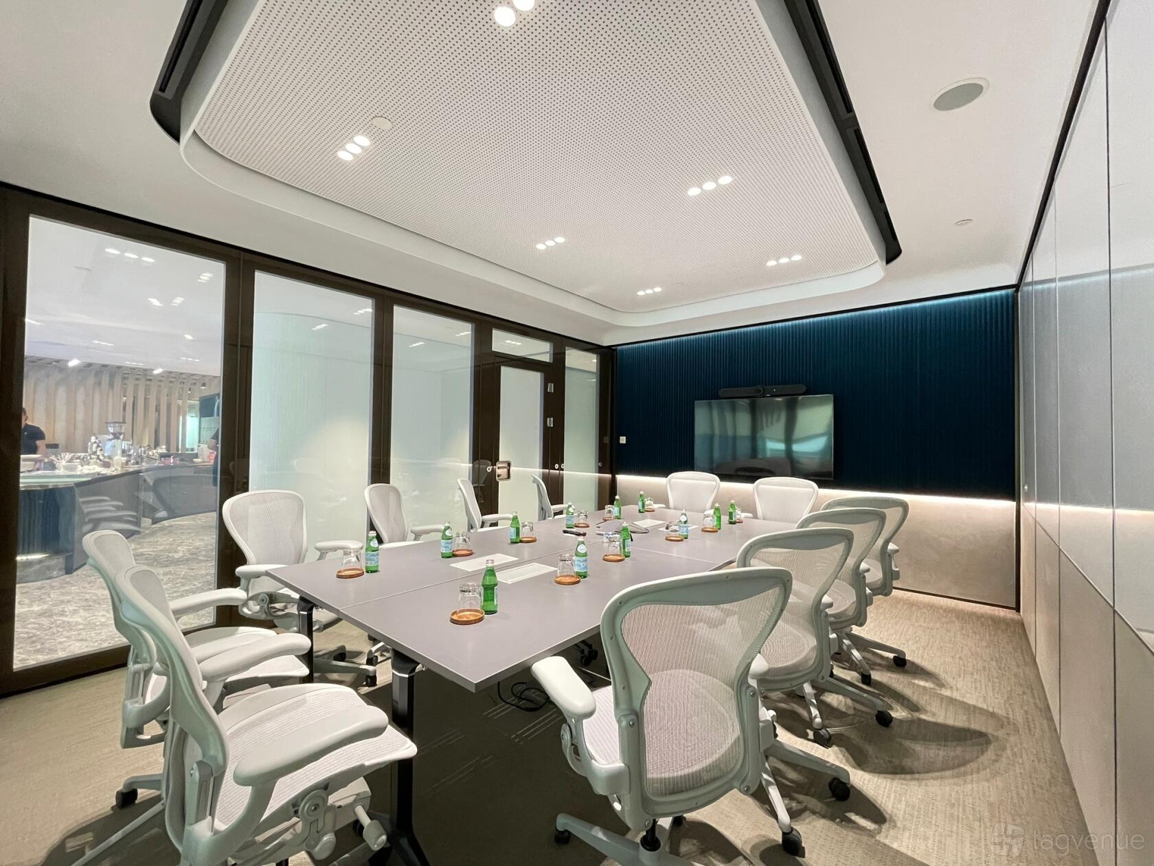 A meeting centre with a long conference table, ergonomic chairs, and built-in video screen at Capital Square.