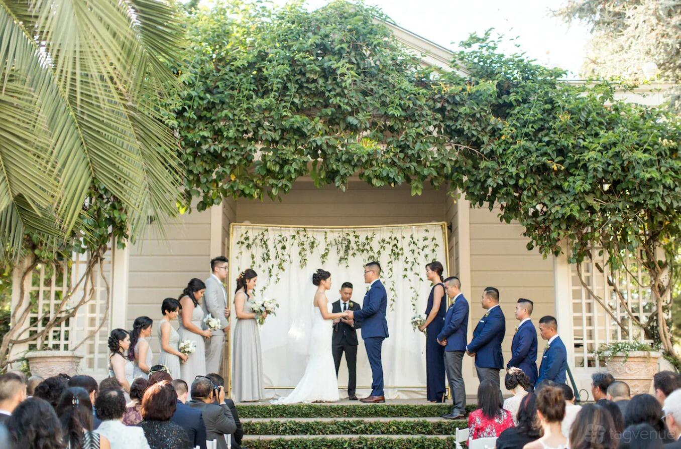 An event venue with a vine-covered pavilion and raised stage used for an outdoor ceremony at Preservation Park.