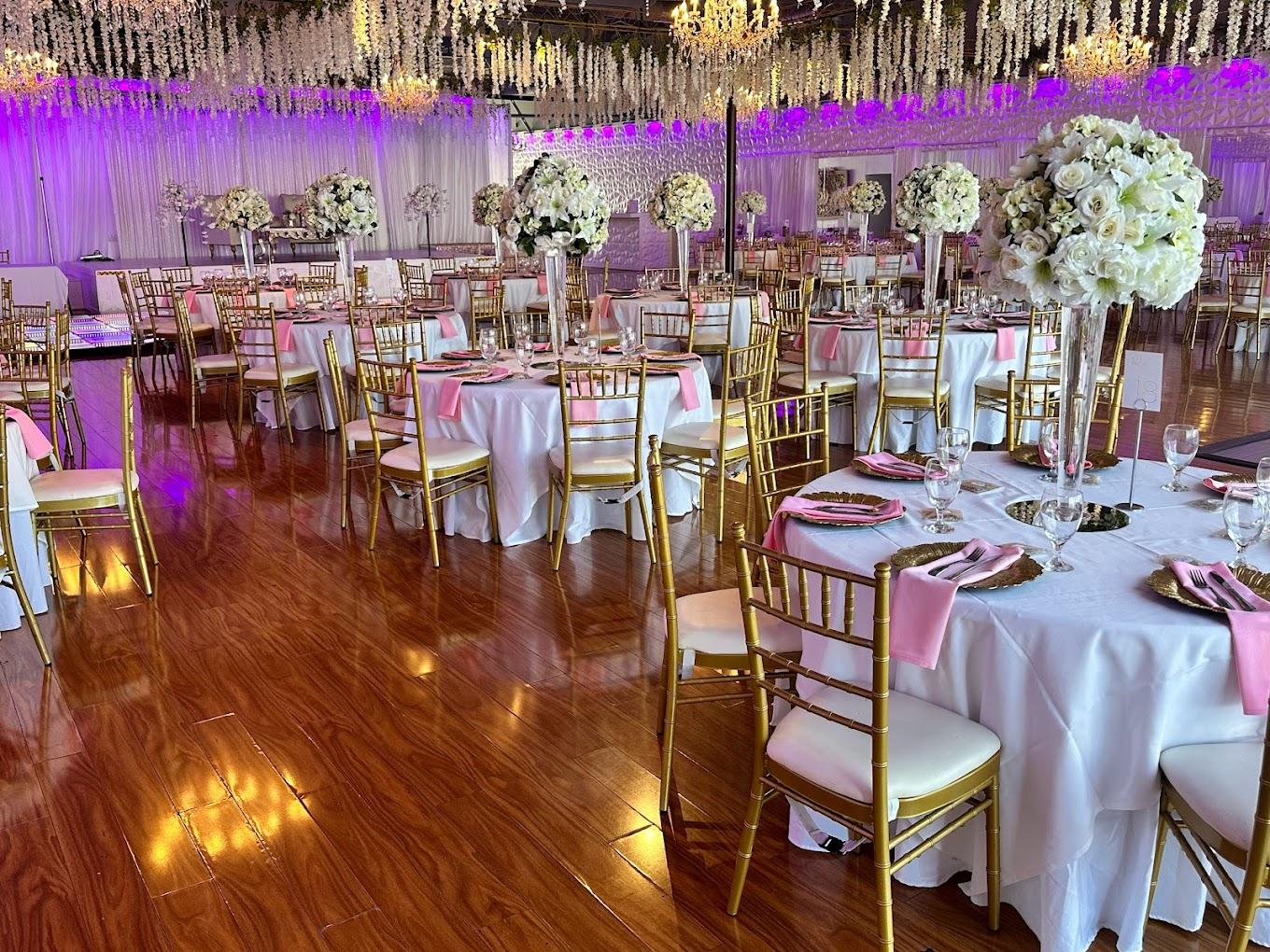 A banquet hall with round tables, gold chairs, pink napkins, and tall floral centerpieces at Royal Banquet Hall & Conference Center.