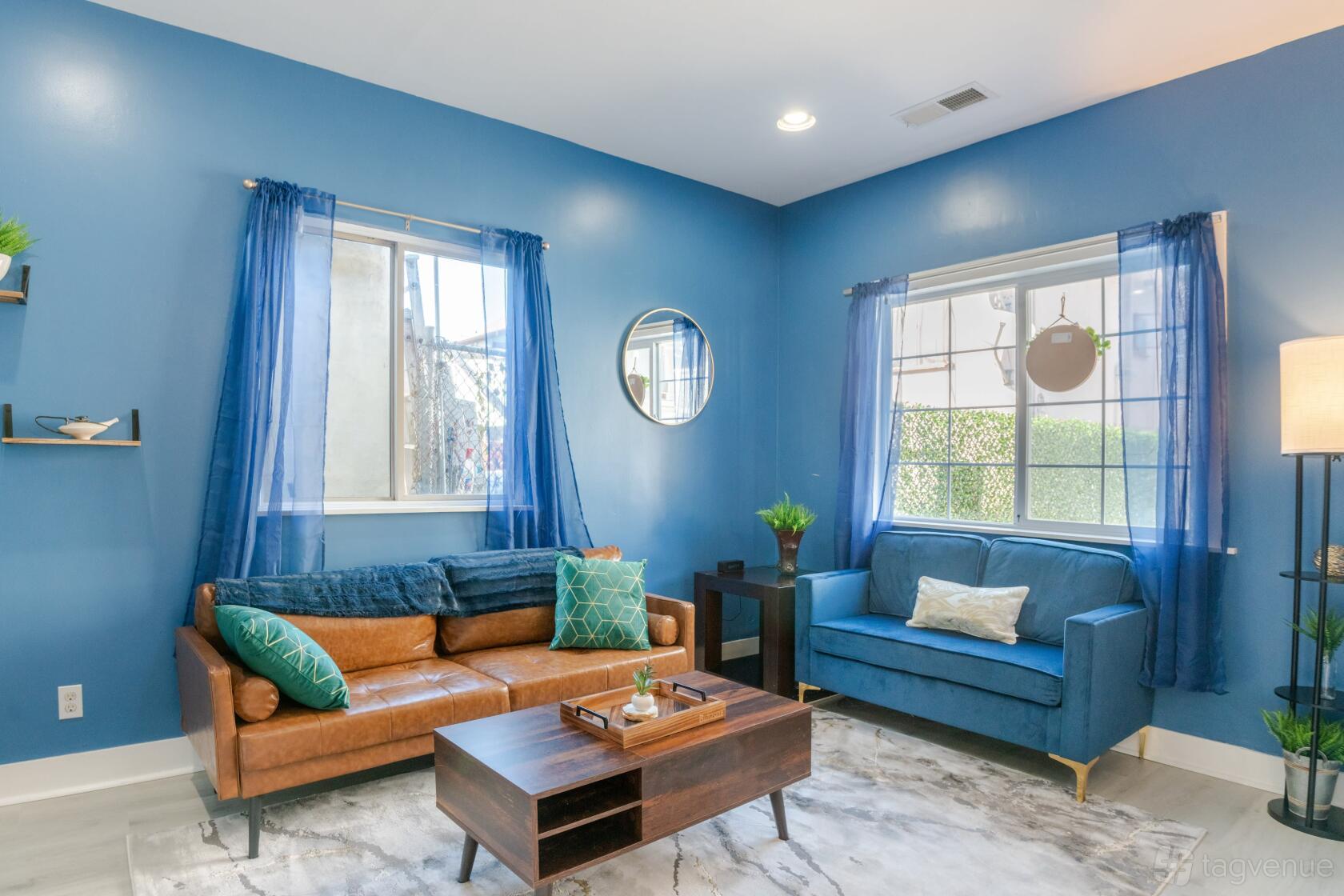 An event venue with a blue living area, leather sofa, blue loveseat, and natural light at Mosswood Cottage.