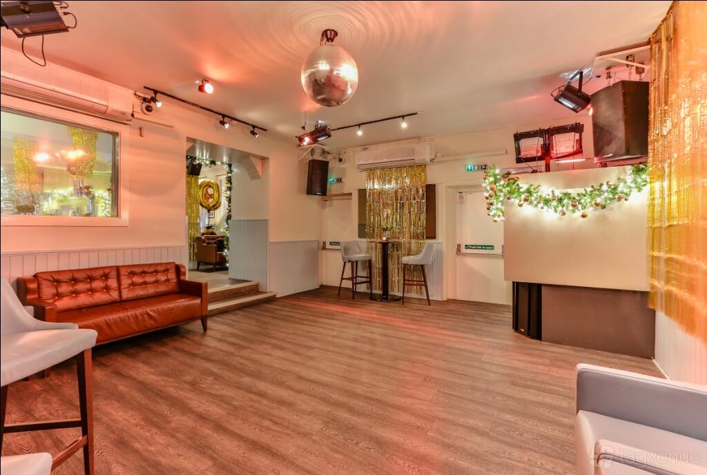 A function room with wood floors, a mirrored disco ball, leather seating, and decorative lights at The Chapel Bar.