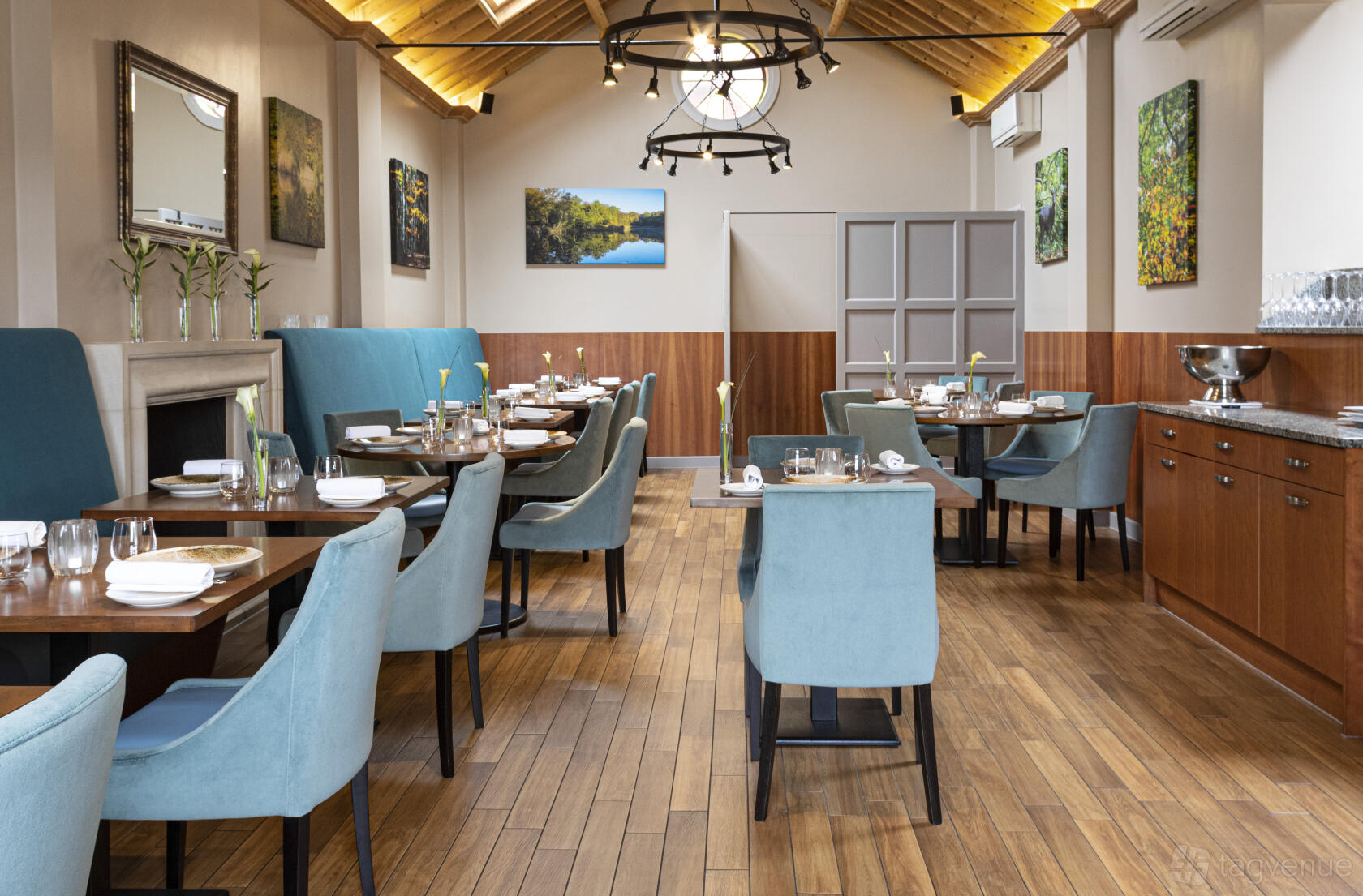 A restaurant meeting room with light blue chairs, wooden floor, and vaulted ceiling with skylights at Haywards.