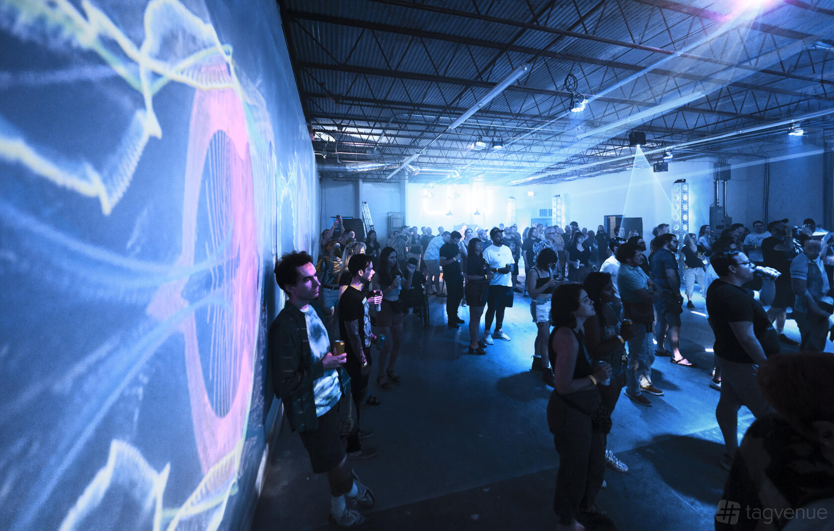 An event venue with projection art on the wall, exposed ceiling beams, and blue ambient lighting at dadaLab.