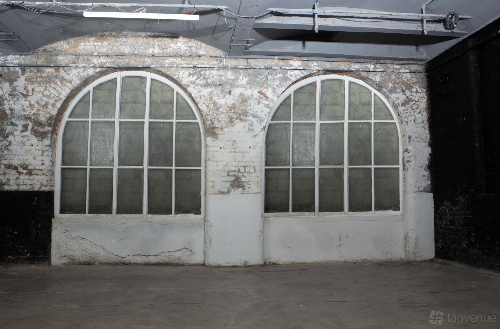 A warehouse with arched industrial windows and exposed brick walls at Submerged Spaces.