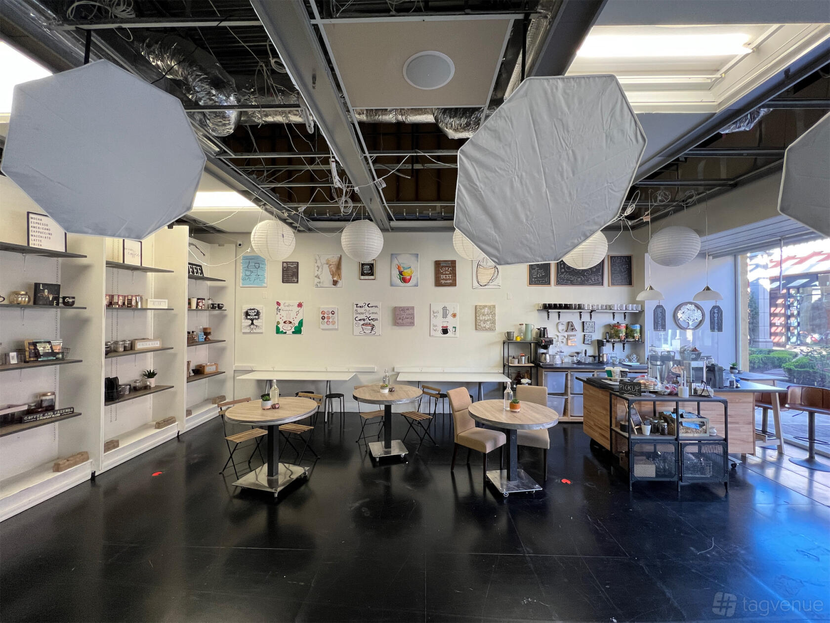 A cafe with hanging paper lanterns, exposed ceiling beams, and round wooden tables at Office, Cafe, Home, Standing Sets Studio.