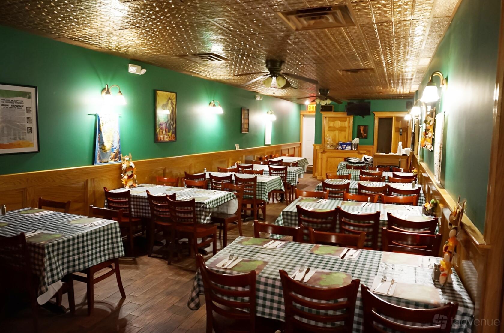 A pub event room with green-checkered tablecloths, wooden chairs, green walls, and a pressed-tin ceiling at Joyce's Tavern.