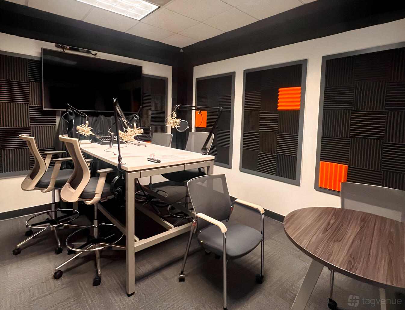 A creative space with a podcast recording table, microphones, and soundproof foam panels at Atlanta Tech Park.