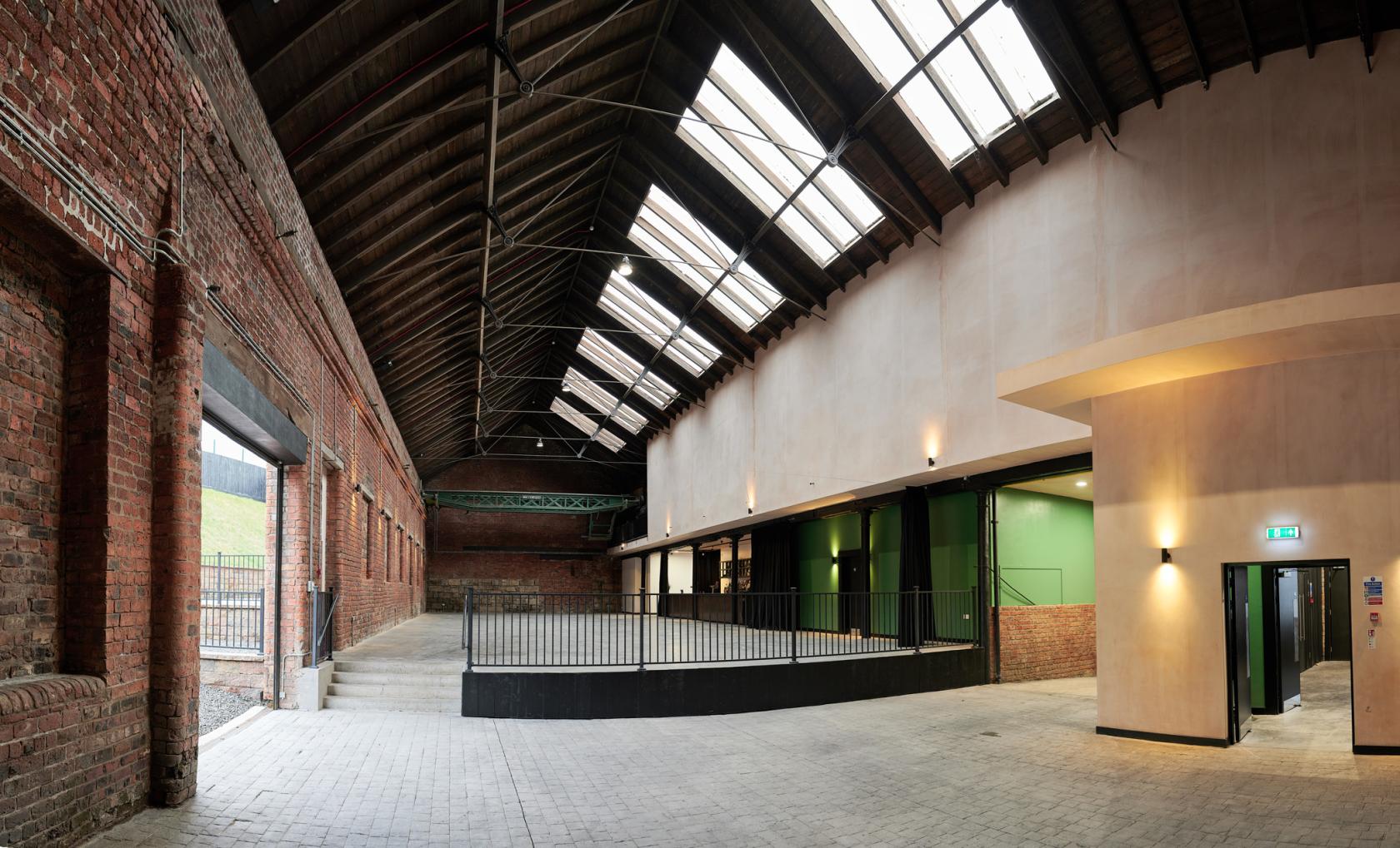 An event venue with exposed brick walls, high vaulted ceiling, and large skylights at The Engine Works.