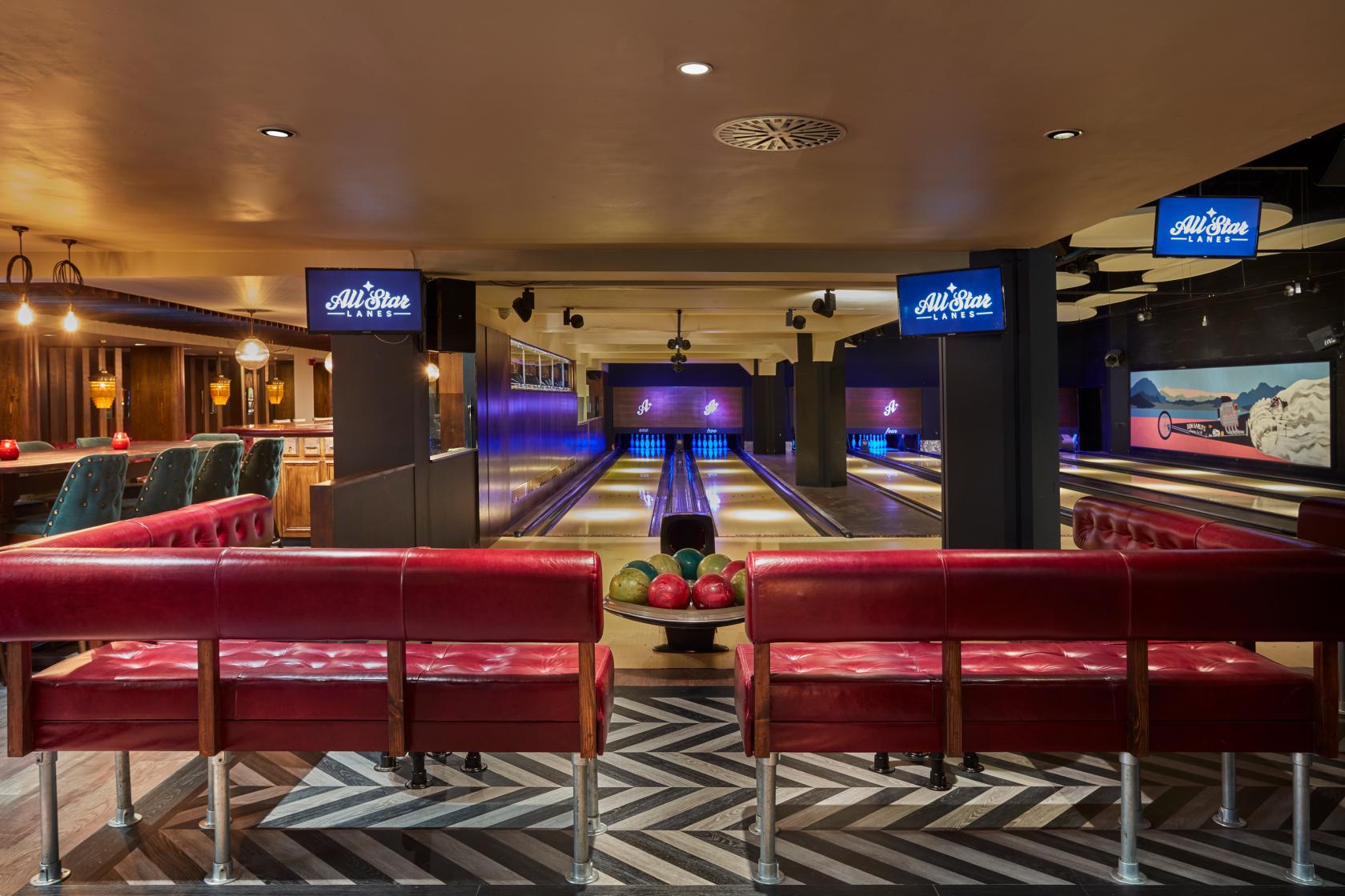 An event venue with bowling lanes, red leather seating, and neon lighting at All Star Lanes Brick Lane.