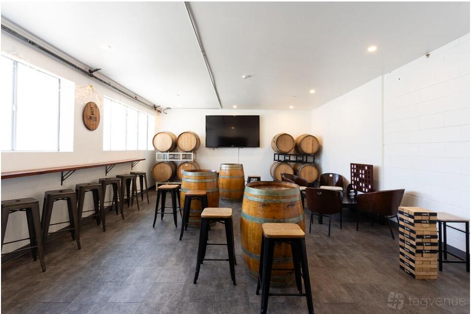 A function room with barrel tables, high stools, and a wall-mounted TV at Lawless Brewing Co.