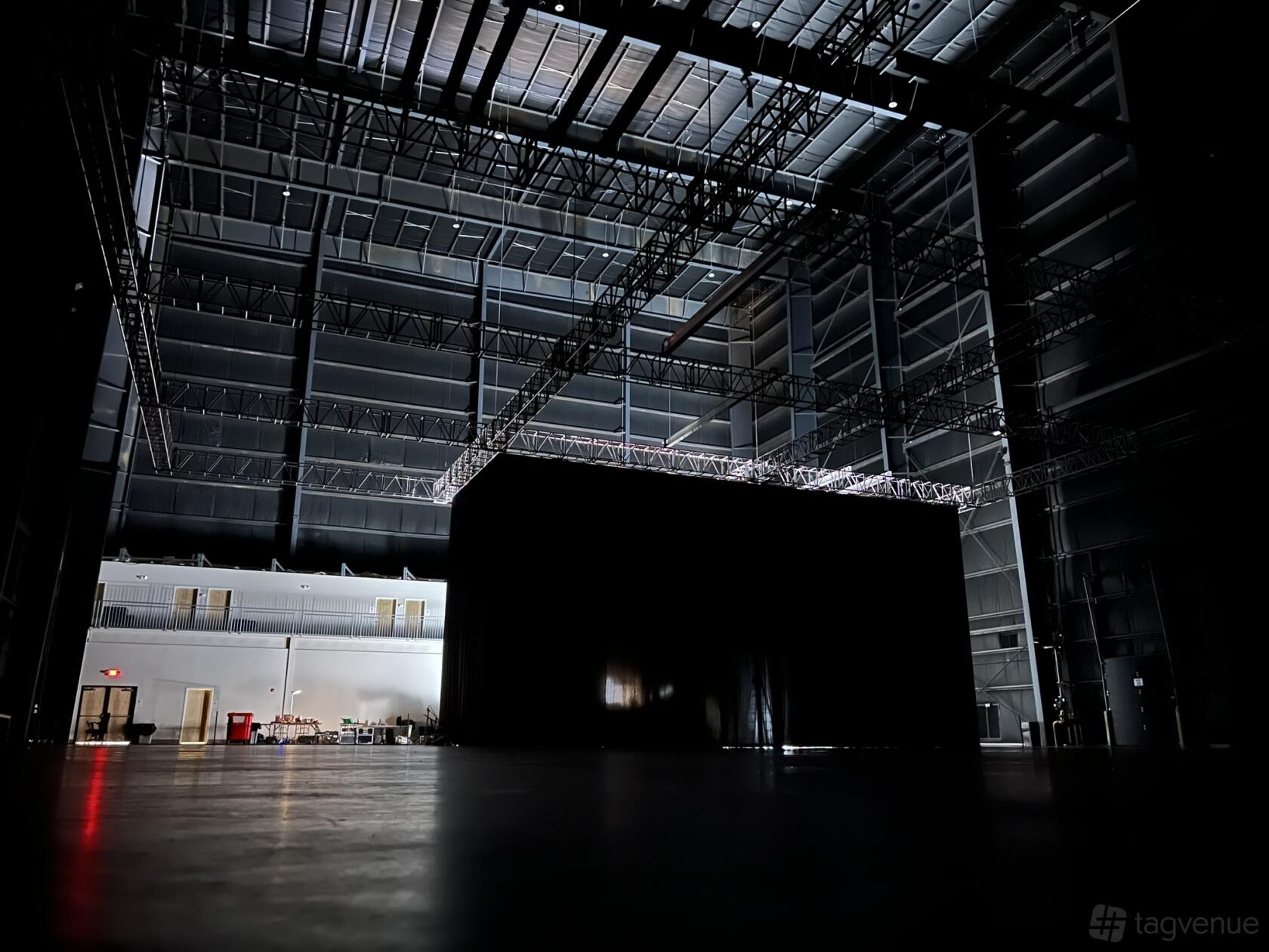 A film studio with high ceilings, metal truss rigging, and a central enclosed set at Pine Box Studios.