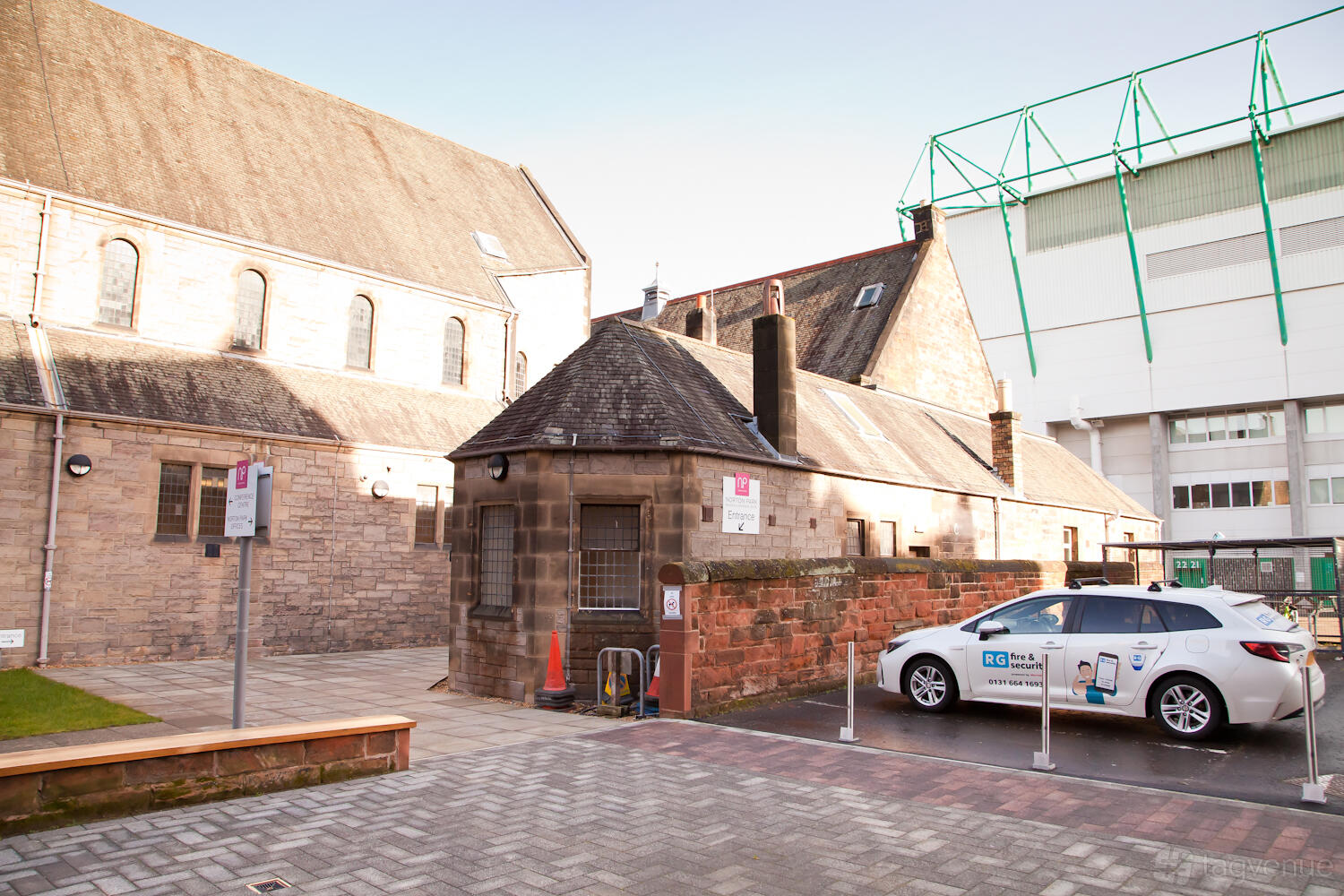 A conference centre with historic stone buildings, a paved walkway, and an electric car charging point at Norton Park Conference Centre.