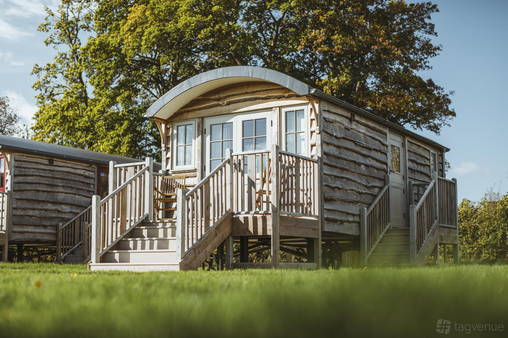 A rustic barn venue with a wooden cabin featuring a front porch and stairs at Hornington Manor.