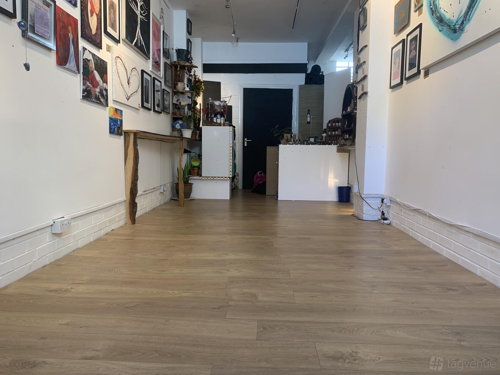 An art gallery event space with wooden floors, white walls, and art displays at Sunflower Studio.