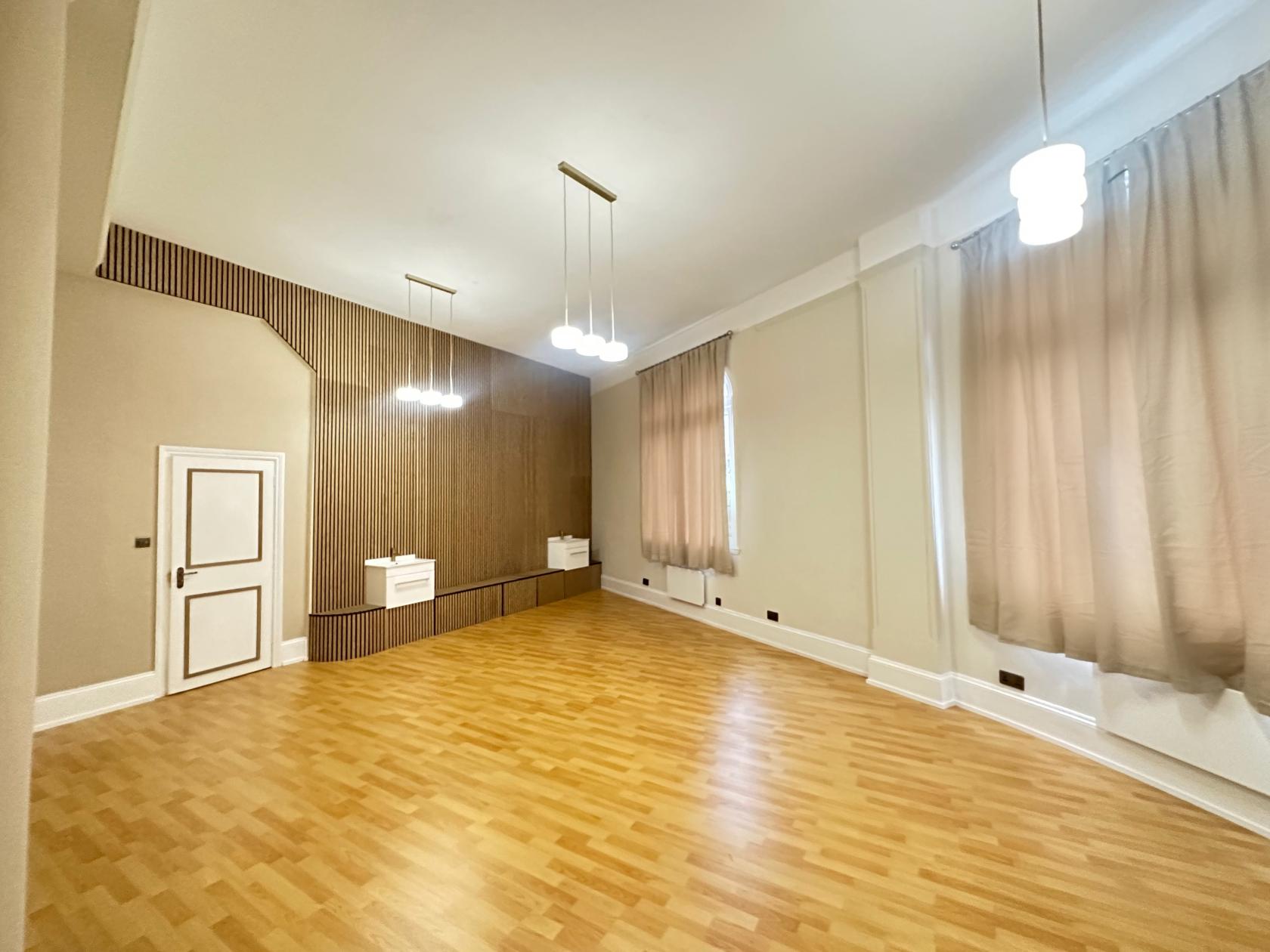 An event venue with wood flooring, pendant lighting, sheer drapes, and a raised platform at Yemaya London Beauty.